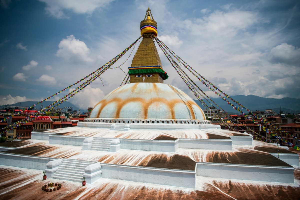 Boudhanath Stupa in Kathmandu, Nepal, with its white dome, Buddha eyes, and colorful prayer flags.