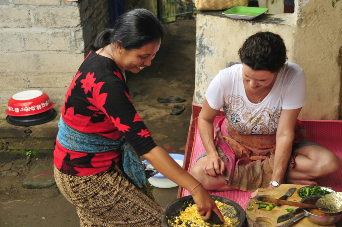A local Nepali woman teaches a visitor to prepare traditional food during a cooking class.