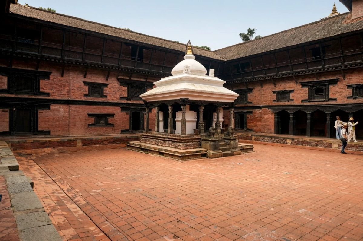 Keshav Narayan Chowk courtyard at Patan Museum surrounded by traditional Newari brick buildings and carved wooden windows.