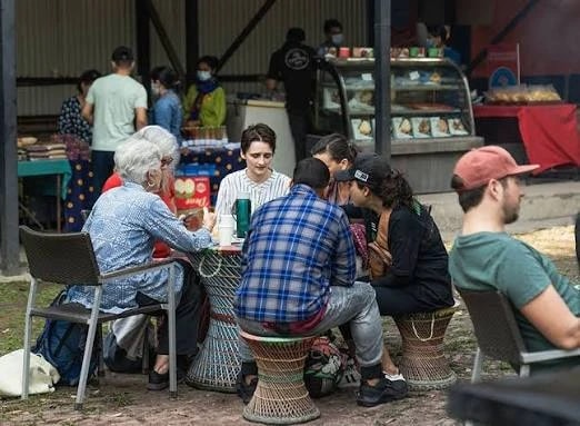 Visitors enjoy food and conversation at an outdoor market stall in Le Sherpa farmer's market, Nepal.